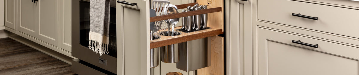 Walnut utensil and knife pull-out open beside a range in a painted kitchen