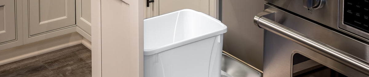 Pull-out kitchen waste system with white bin extended from a cabinet beside a range
